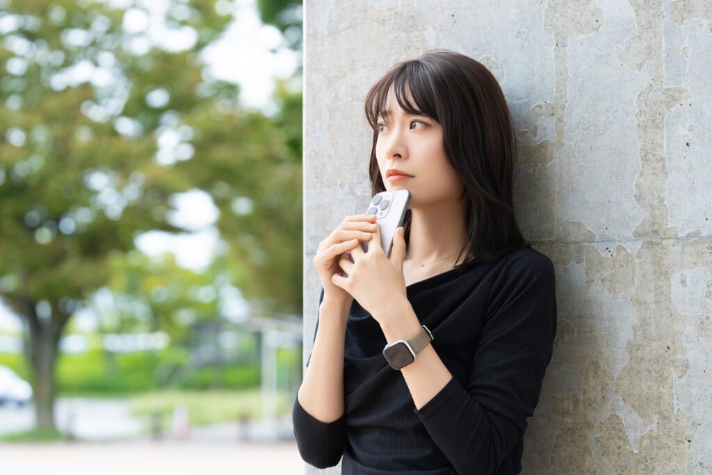 スマホを持ちながら待っている女性